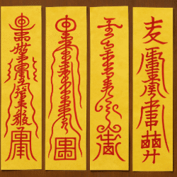 Four vertical Taoist talismans painted in red ink on yellow paper, displayed against a wooden background.